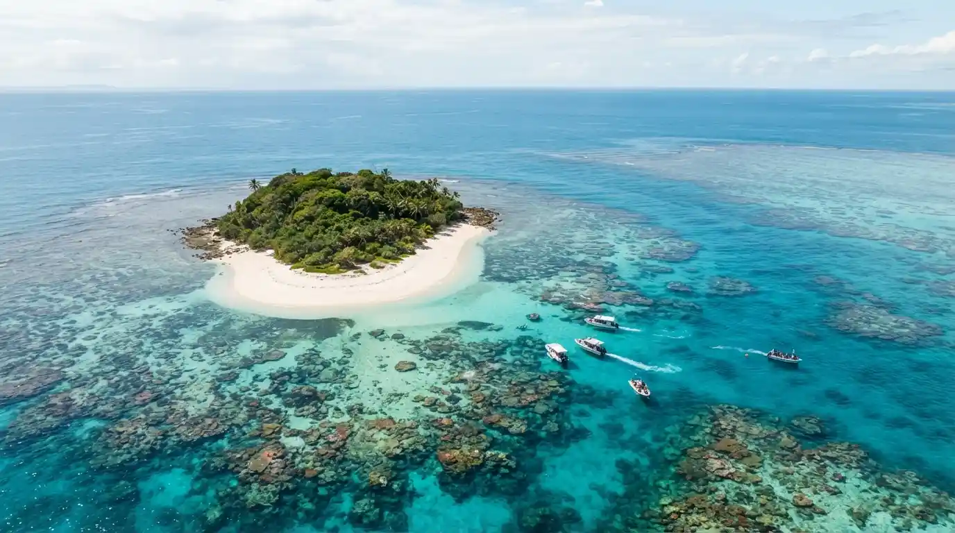 Aerial view of a tropical Great Barrier Reef island surrounded by clear turquoise water and visible coral formations